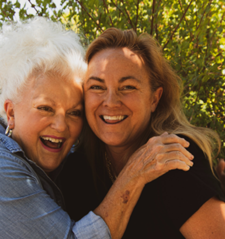 A woman hugging a smiling woman.