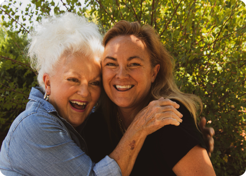 A woman hugging a smiling woman.