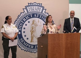 A woman standing at a podium with a man and a woman standing behind her.