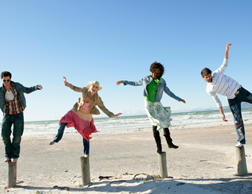 A group of people jumping in the air on a beach.