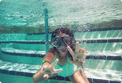 Young girl showing a peace sign while swimming under water. 