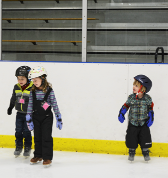 A person and a group of kids on an ice rink.