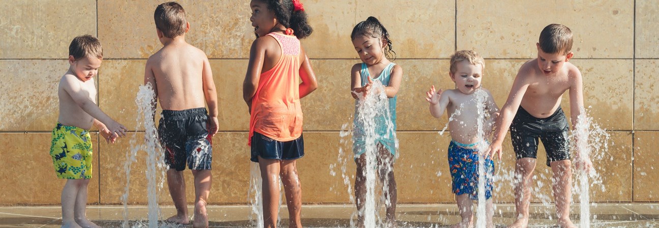A group of children playing in a water fountain.